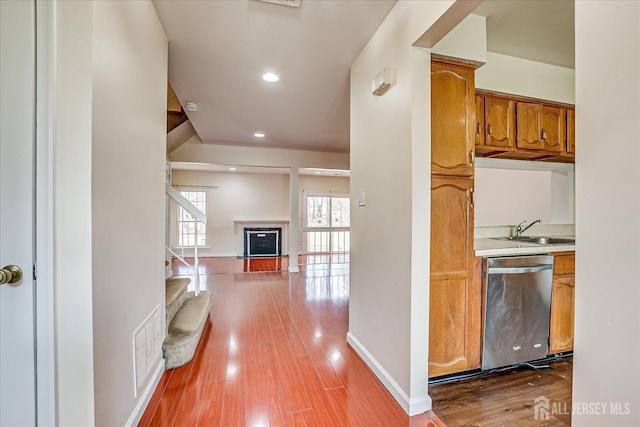 kitchen with visible vents, wood finished floors, light countertops, stainless steel dishwasher, and a sink