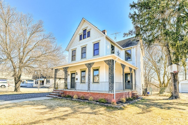 view of front facade featuring covered porch and a chimney