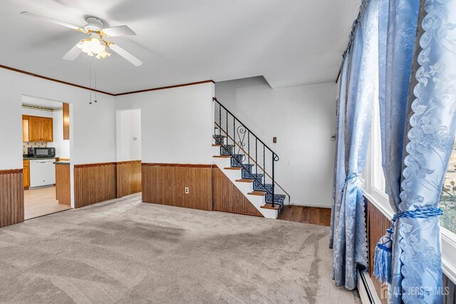 interior space with ceiling fan, baseboard heating, crown molding, and carpet flooring