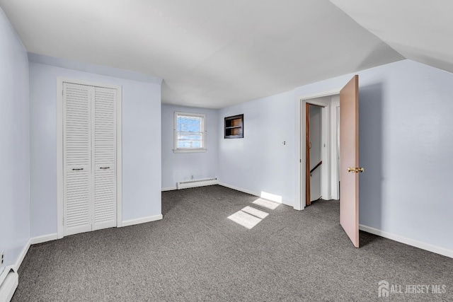 unfurnished bedroom with lofted ceiling, baseboard heating, a closet, and dark carpet