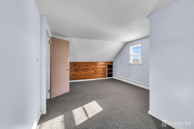 bonus room featuring a baseboard heating unit, dark colored carpet, and vaulted ceiling