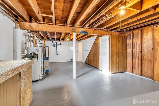 basement with water heater and wooden walls