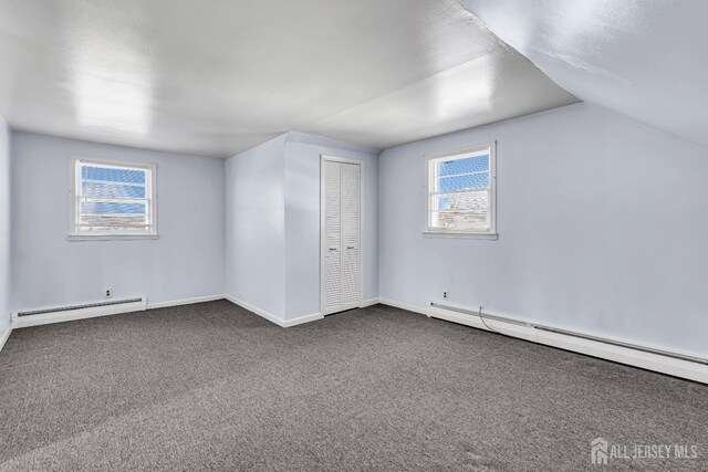 additional living space with plenty of natural light, a baseboard radiator, lofted ceiling, and carpet flooring