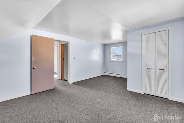 unfurnished bedroom with a closet, lofted ceiling, dark carpet, and a baseboard radiator