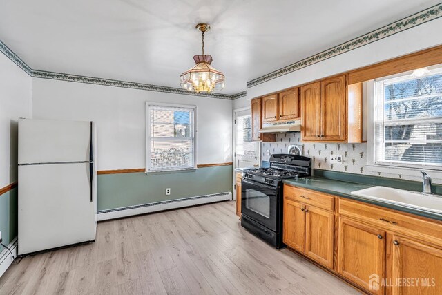 kitchen featuring decorative light fixtures, white fridge, sink, black gas stove, and a baseboard radiator