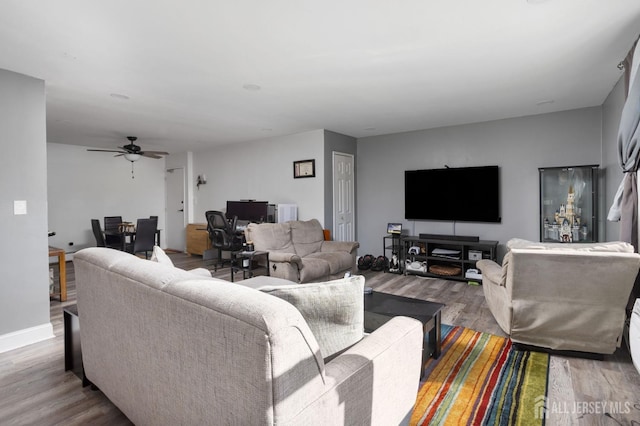 living room with a ceiling fan, baseboards, and wood finished floors