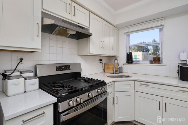 kitchen featuring crown molding, stainless steel gas stove, a sink, white cabinetry, and under cabinet range hood