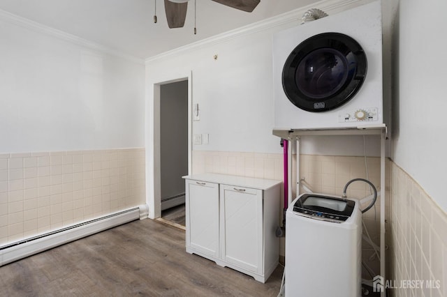 laundry room featuring tile walls, a baseboard heating unit, and stacked washer / dryer