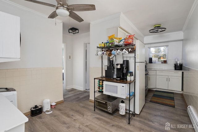 kitchen with white microwave, crown molding, a baseboard heating unit, and wood finished floors