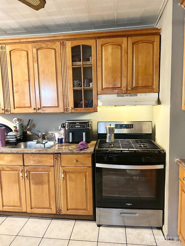 44 S Ward St, New Brunswick, NJ 08901 - kitchen featuring gas range, under cabinet range hood, glass insert cabinets, light tile patterned flooring, and brown cabinetry