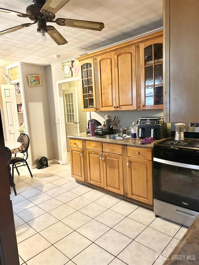44 S Ward St, New Brunswick, NJ 08901 - kitchen with stainless steel gas range, a ceiling fan, light tile patterned floors, glass insert cabinets, and brown cabinetry