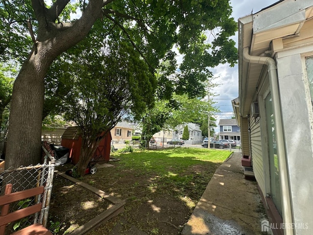 view of yard with fence, a storage shed, an outbuilding, and a residential view