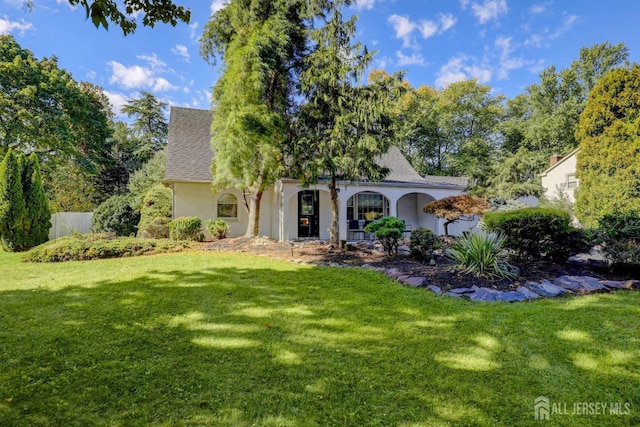 view of front of house featuring stucco siding, a front yard, and roof with shingles