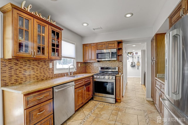 kitchen with visible vents, brown cabinets, a sink, appliances with stainless steel finishes, and decorative backsplash