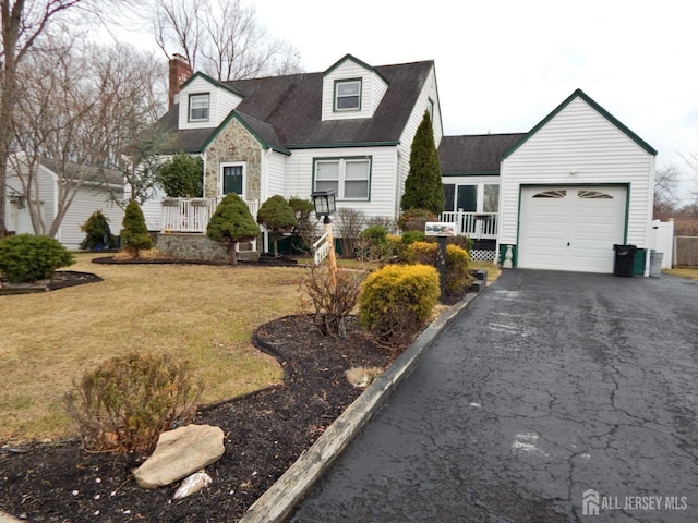 cape cod home with aphalt driveway, a chimney, a garage, stone siding, and a front lawn