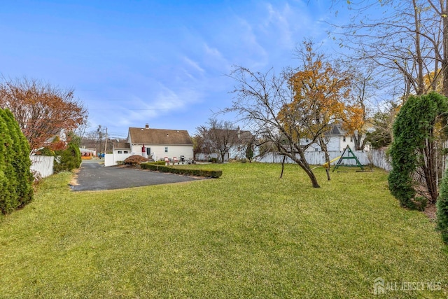 view of yard with aphalt driveway and fence