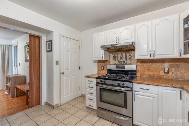 kitchen with light tile patterned floors, stainless steel range with gas stovetop, under cabinet range hood, and white cabinetry