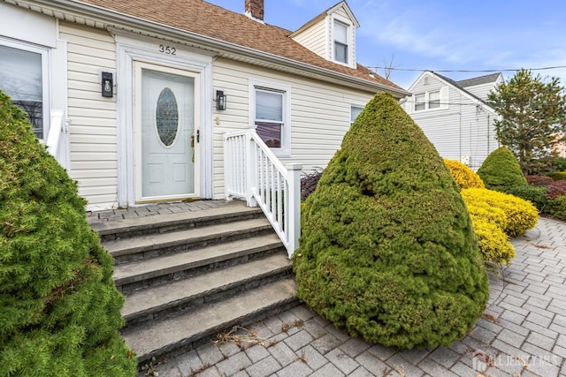 doorway to property with roof with shingles