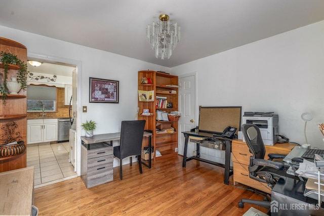 home office featuring a notable chandelier, a sink, and light wood finished floors