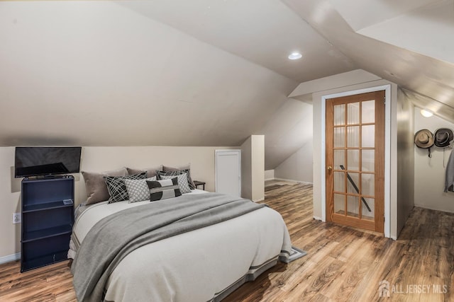 bedroom featuring lofted ceiling, baseboards, and wood finished floors