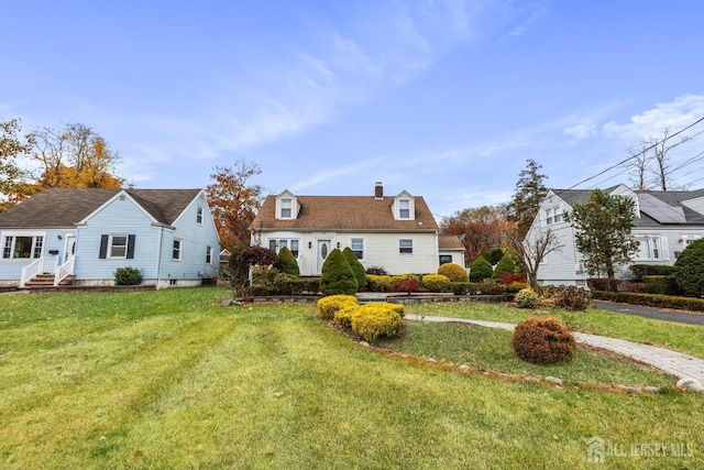 cape cod-style house featuring a chimney and a front yard