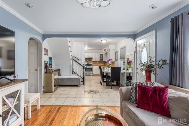 living room with arched walkways, light tile patterned floors, stairs, and ornamental molding