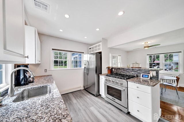 10 Shaw Dr, Franklin, NJ 08528 - kitchen with appliances with stainless steel finishes, baseboard heating, white cabinetry, light wood-style floors, and a peninsula