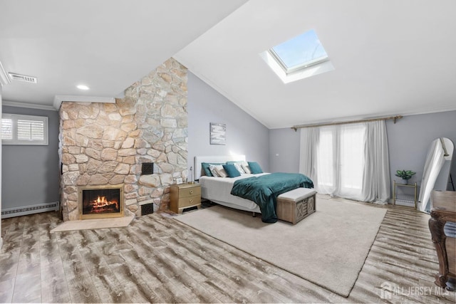 bedroom featuring wood finished floors, a baseboard radiator, vaulted ceiling with skylight, a fireplace, and ornamental molding