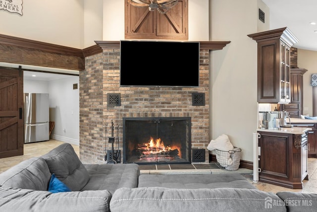 living area with visible vents, baseboards, crown molding, a barn door, and a brick fireplace