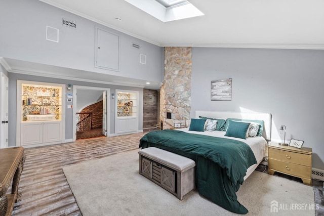 bedroom featuring wood finished floors, vaulted ceiling with skylight, crown molding, a baseboard radiator, and baseboards