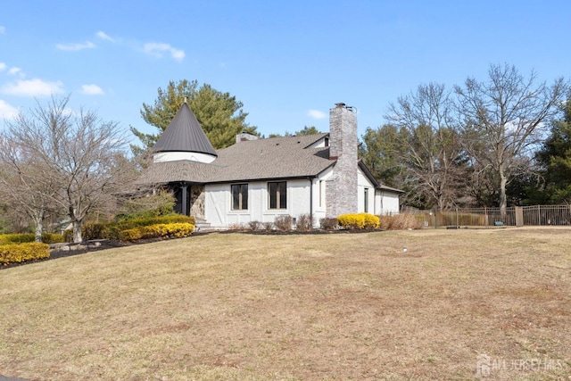 view of front facade featuring a chimney, a front yard, and fence