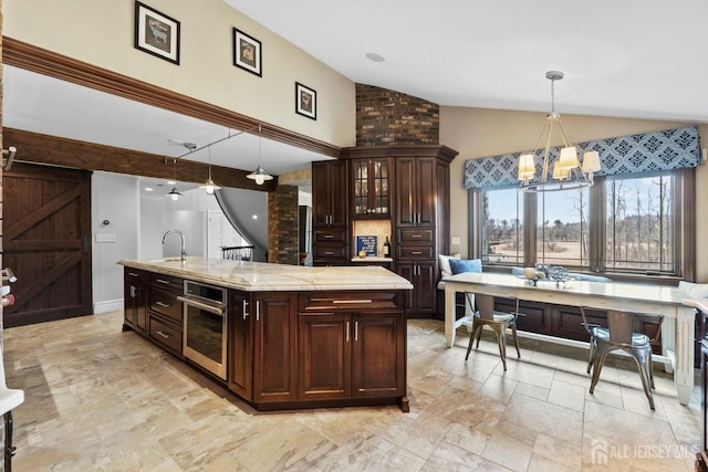 kitchen with oven, decorative light fixtures, a sink, a barn door, and vaulted ceiling