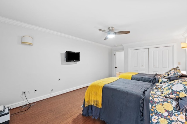 bedroom with wood finished floors, baseboards, a closet, and ornamental molding