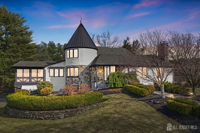 view of front of home featuring stucco siding, a lawn, metal roof, stone siding, and a standing seam roof