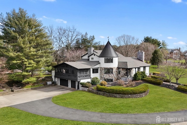 view of front of property featuring a front yard, a chimney, a garage, stone siding, and driveway