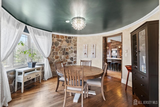 dining space featuring visible vents, a notable chandelier, wood finished floors, and ornamental molding