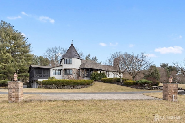 view of front facade with a front lawn, stucco siding, metal roof, a sunroom, and a standing seam roof