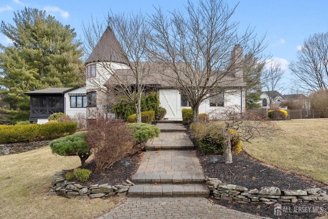 view of front facade with a front yard, a sunroom, and a chimney