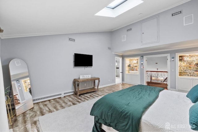 bedroom with wood finished floors, a skylight, a baseboard heating unit, and ornamental molding