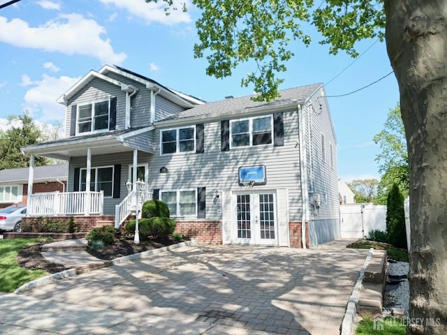 view of front of house featuring french doors, a gate, covered porch, and brick siding