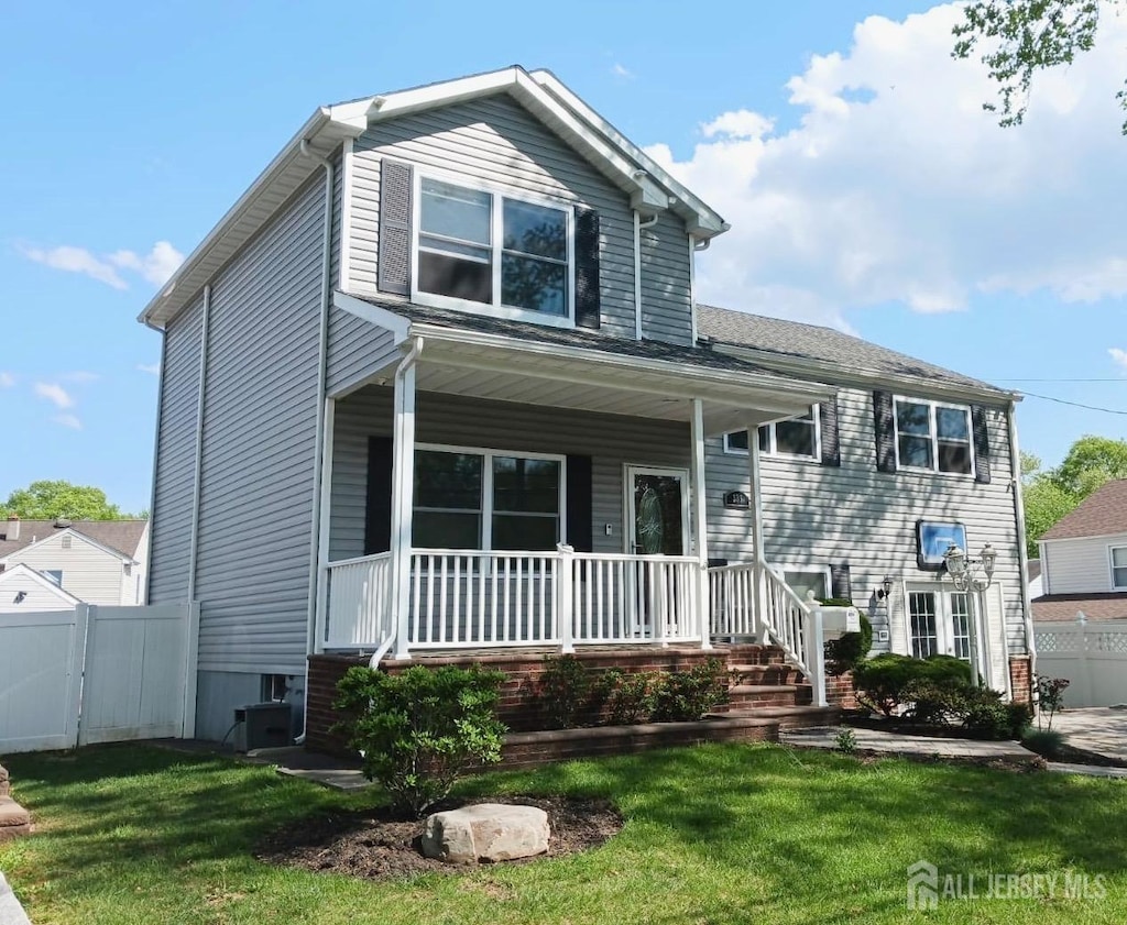 view of front of home with covered porch, fence, and a front lawn