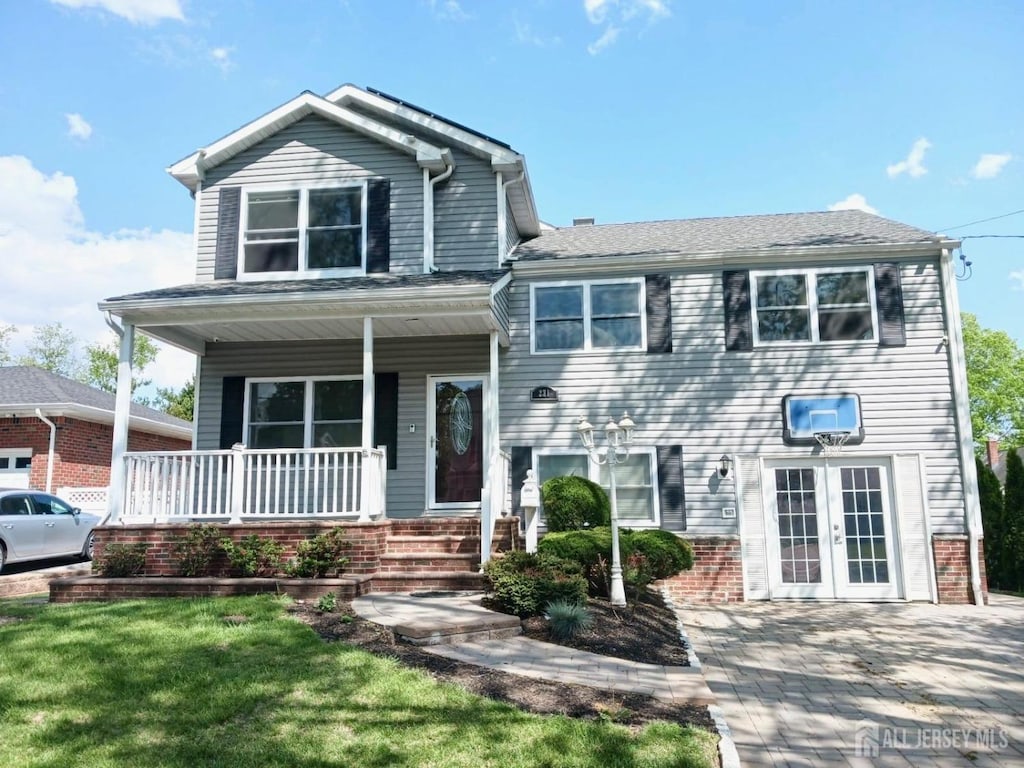 tri-level home featuring a porch, brick siding, and french doors