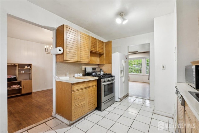 796 Curie Rd, North Brunswick, NJ 08902 - kitchen with stainless steel range with gas stovetop, light countertops, white refrigerator with ice dispenser, a chandelier, and light tile patterned flooring
