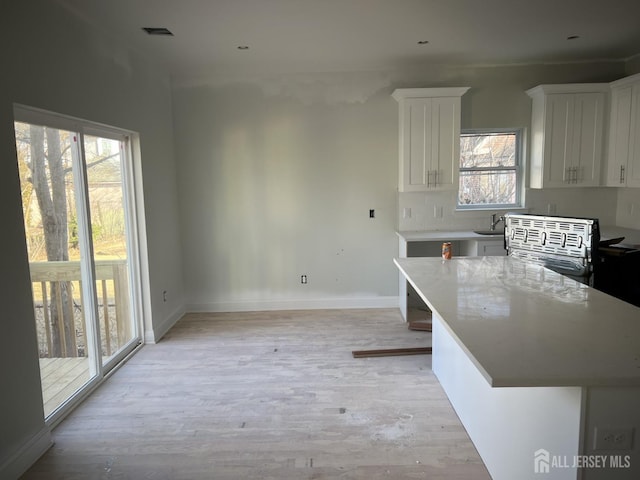 kitchen with a kitchen island, white cabinetry, light wood-type flooring, and a kitchen bar