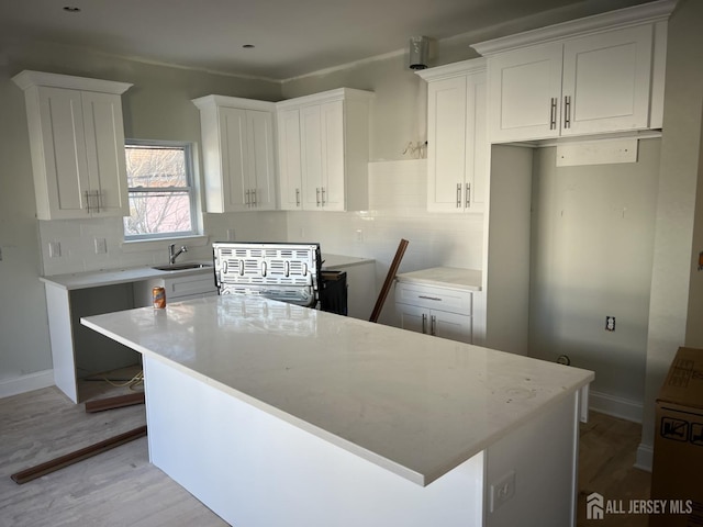 kitchen with sink, light hardwood / wood-style floors, white cabinetry, and a kitchen island