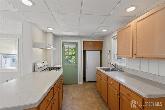 kitchen with recessed lighting, under cabinet range hood, white appliances, a sink, and light countertops