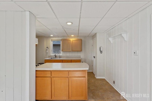 kitchen featuring a drop ceiling, light countertops, recessed lighting, and a sink