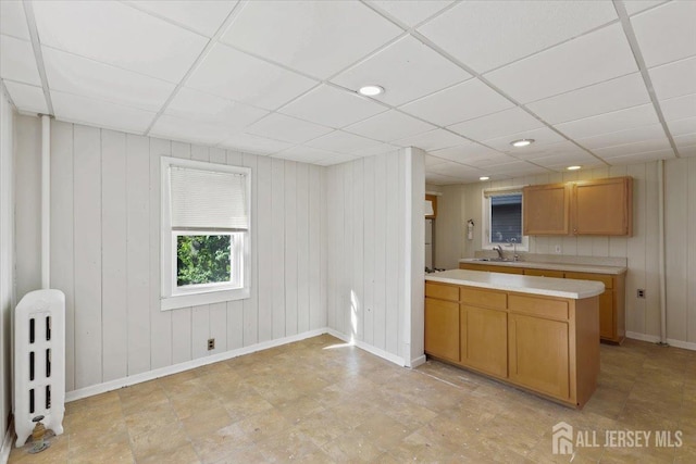 kitchen with a sink, radiator, light countertops, and a paneled ceiling