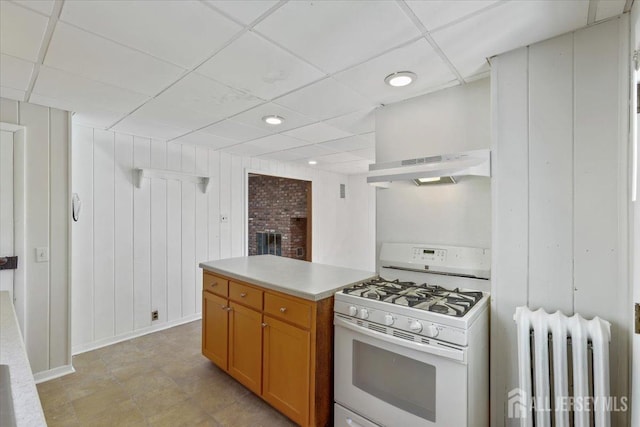 kitchen with a drop ceiling, white range with gas stovetop, under cabinet range hood, radiator heating unit, and open shelves