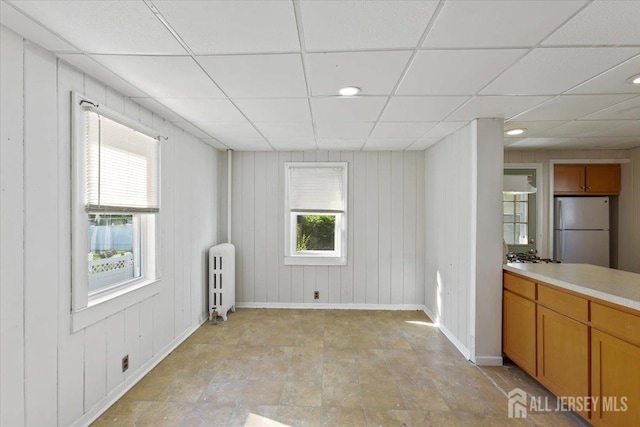 interior space featuring a drop ceiling, recessed lighting, baseboards, and radiator heating unit
